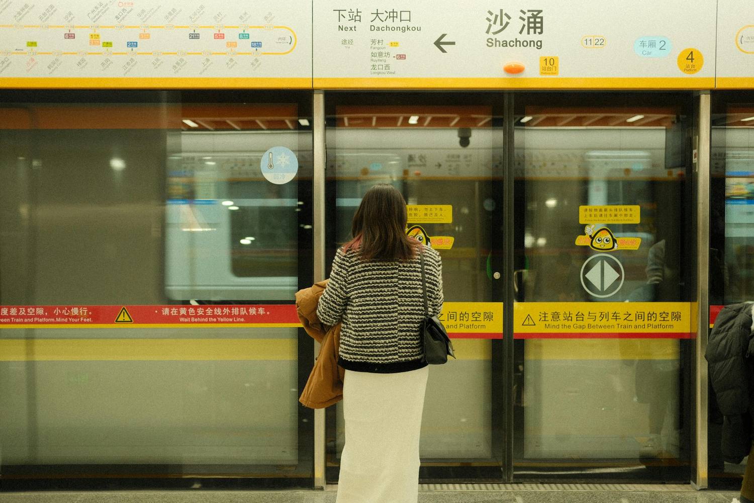 The image shows a woman waiting for a train at the subway